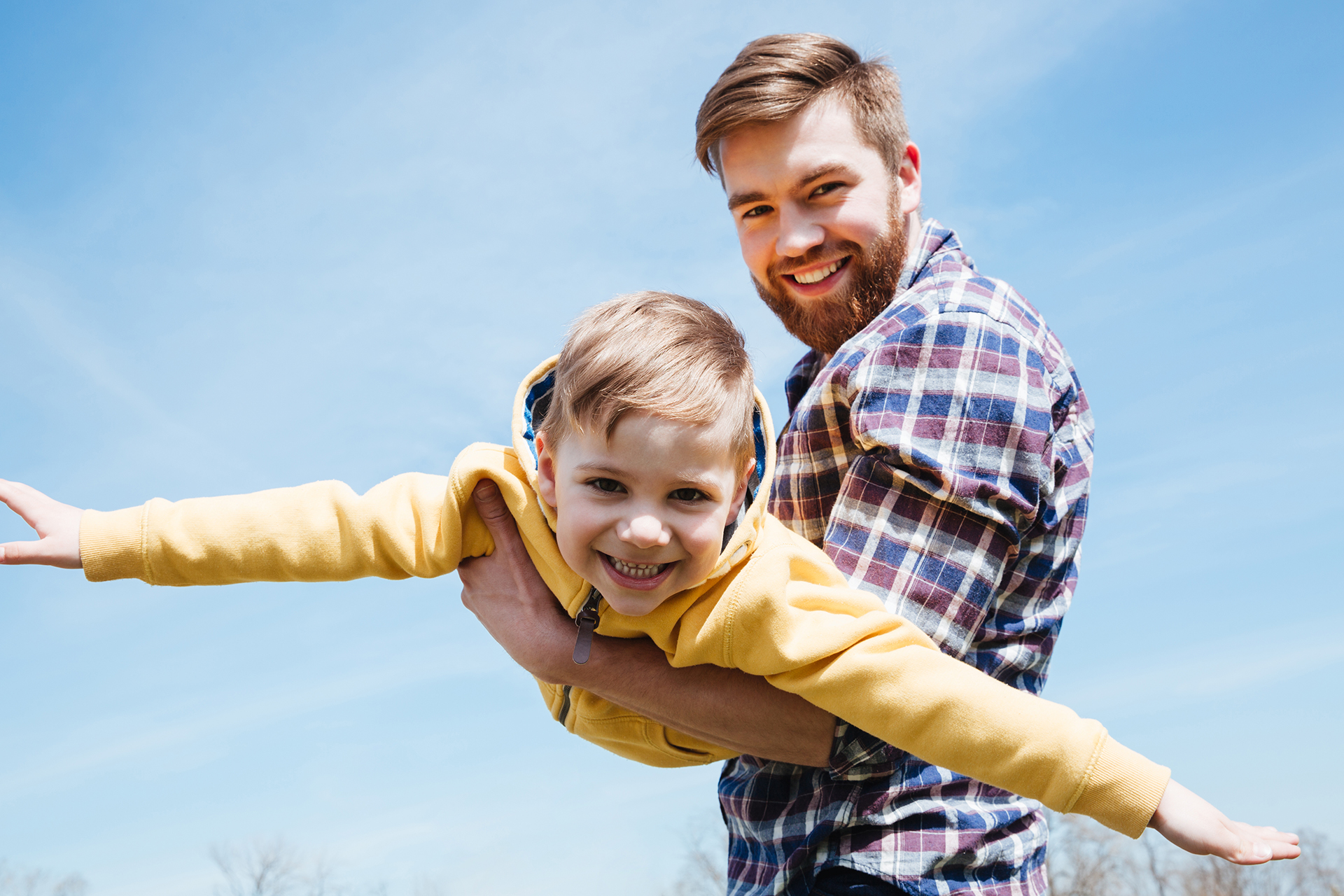 Young smiling father and his little son playing together in a city park