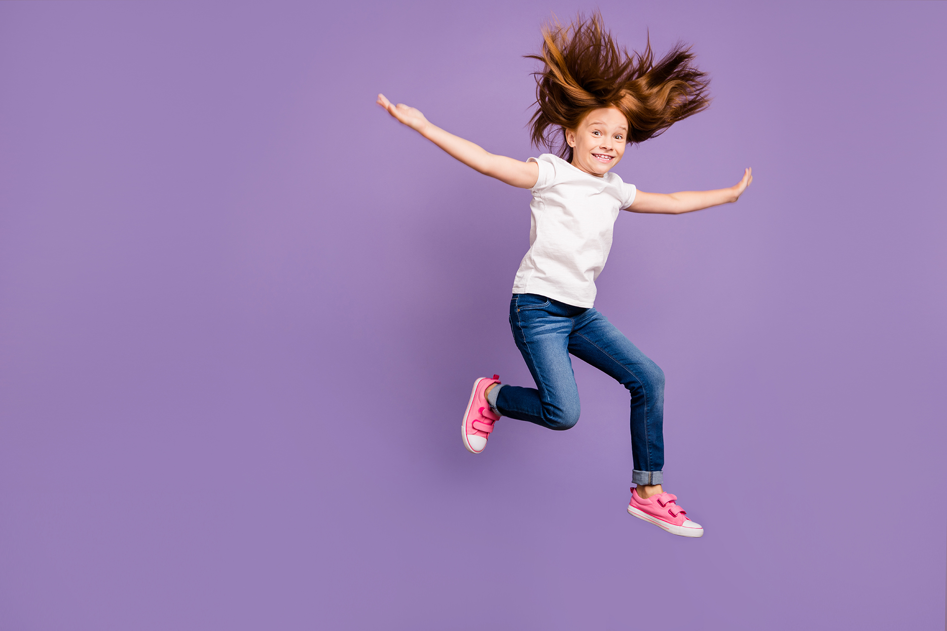 Full body profile photo of funny small foxy lady jumping high rejoicing cheerful mood hairdo flying with warm wind wear casual white t-shirt jeans isolated purple background